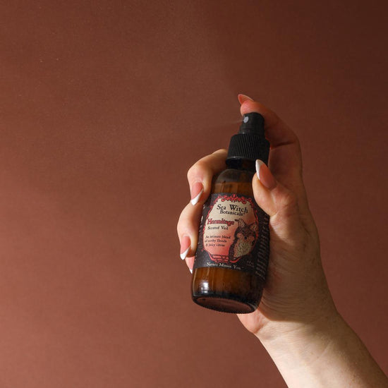 Hand holding a brown glass bottle with a label against a solid background
