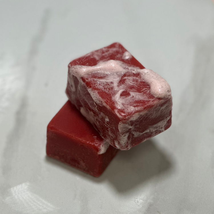 Two red soap bars with white specks on a light gray background