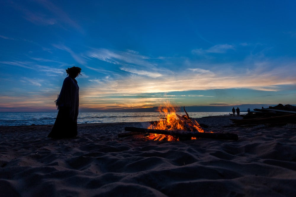 Unrecognizable people celebrating Litha with bonfires on beach