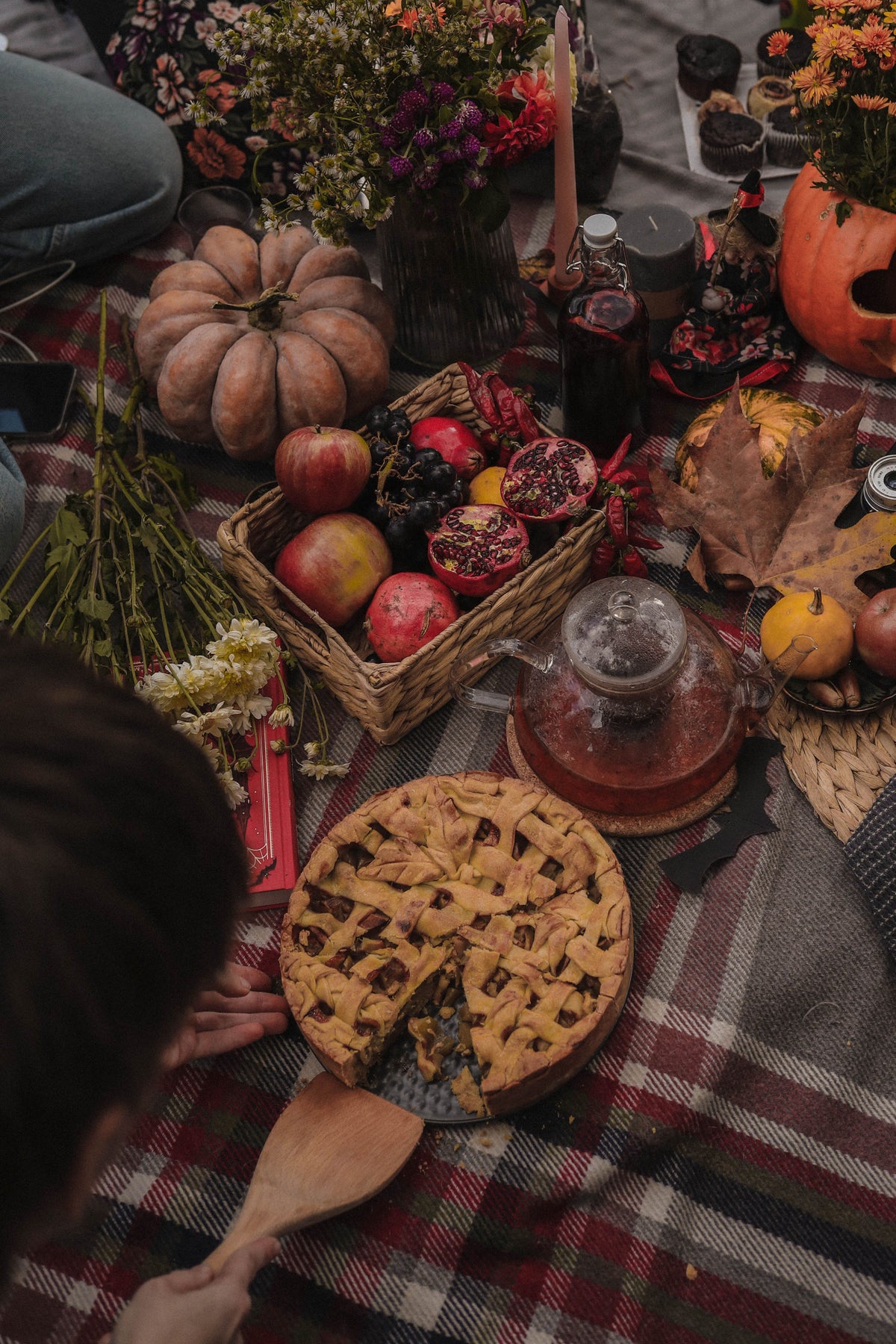 Cozy autumn picnic setup with pie, pumpkins, pomegranates, and fall decor.