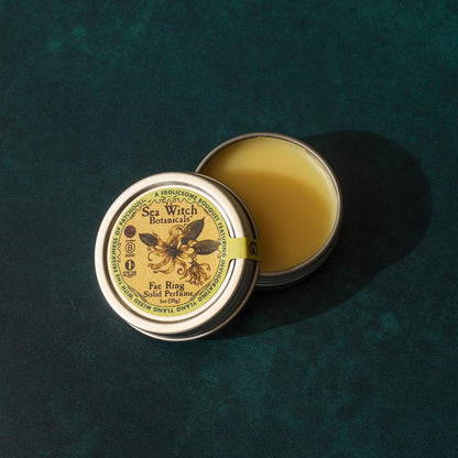 Open tin of Sea Witch Botanicals balm on a textured green background