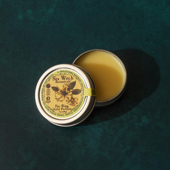 Open tin of Sea Witch Botanicals balm on a textured green background