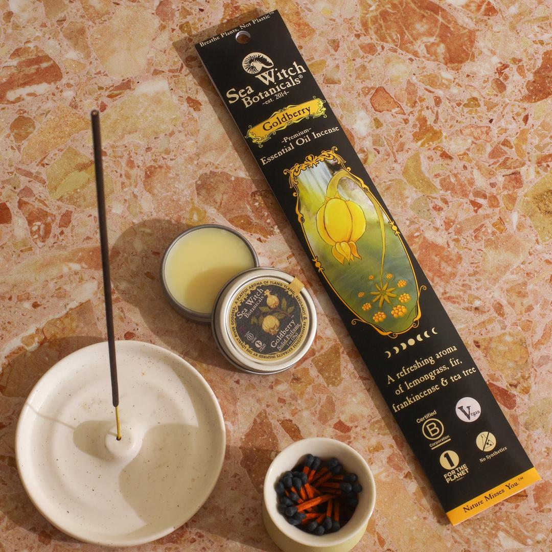 Incense set with incense stick, incense burner, and packaging on a textured surface