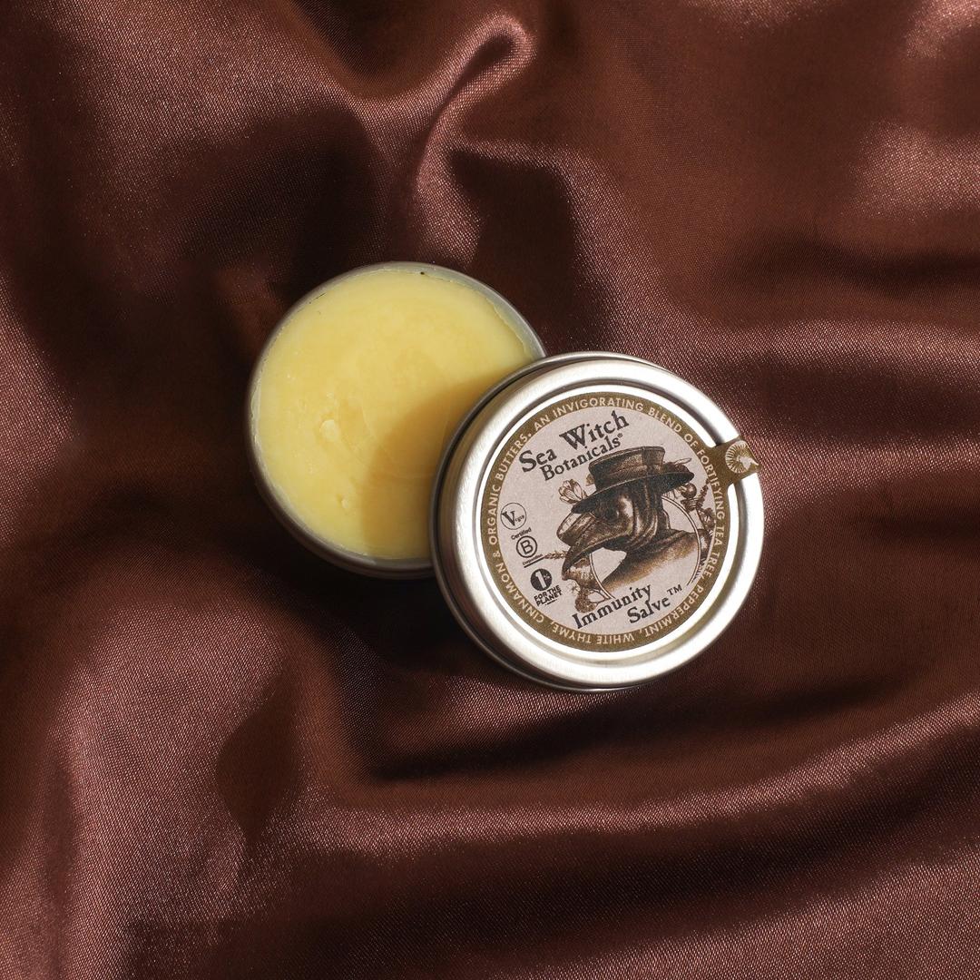 Small jar of balm with a decorative label on a brown fabric background