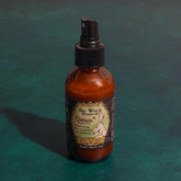 Brown spray bottle with label on a teal background