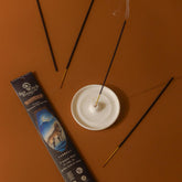Incense sticks with smoke on a brown surface, next to a packaging box.