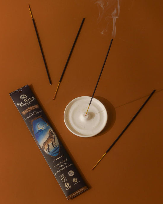 Incense sticks with smoke on a brown surface, next to a packaging box.