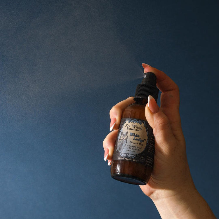 Hand holding a dark glass bottle with a dropper against a dark blue background